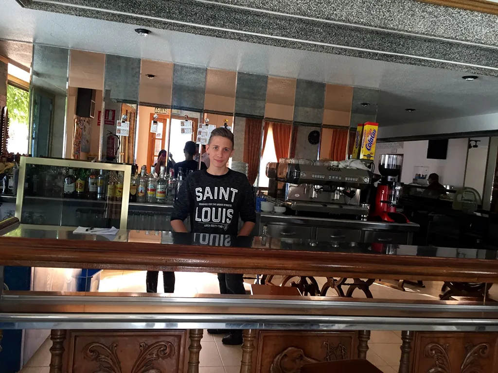 Ein Jugendlicher steht hinter dem Tresen einer Bar.